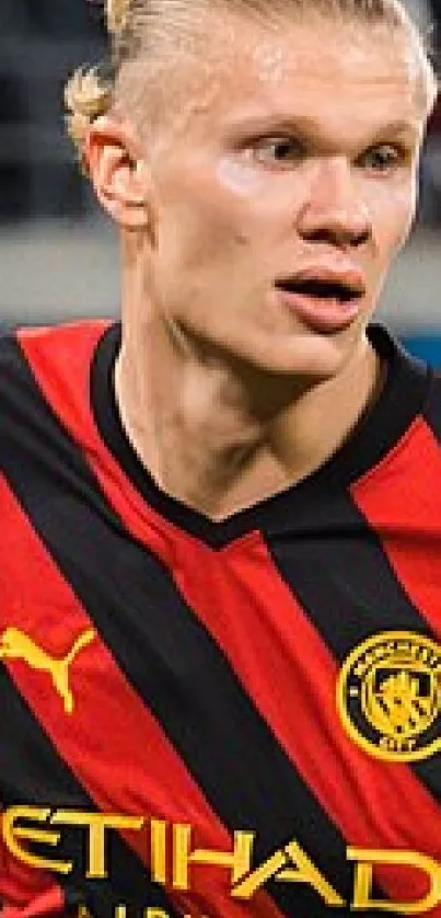 Footballer in red and black jersey running on field.