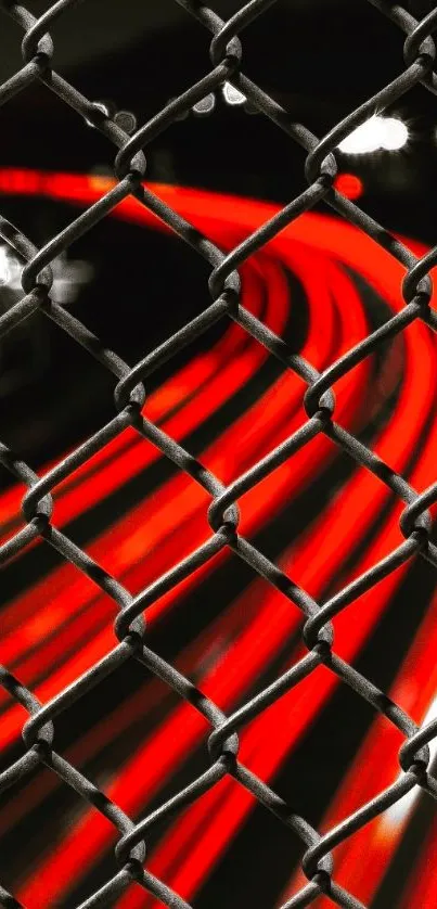 Red light trails through a metal fence at night.