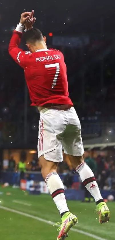 Soccer player jumps celebrating a goal at night stadium.