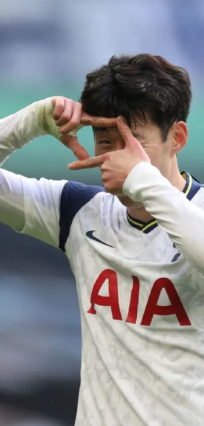 Soccer player forming hand gesture on field in stylish jersey.