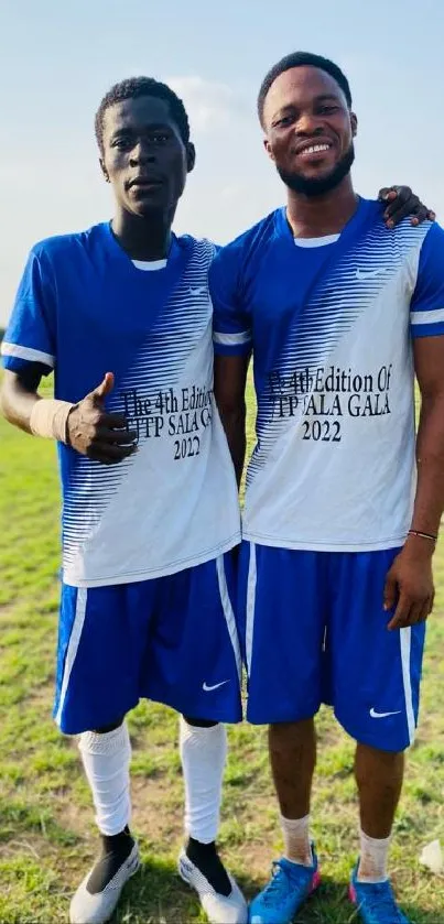 Dynamic duo in blue sports jerseys on a sunny field.