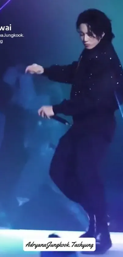 Performer in black attire on vibrant stage with indigo blue lighting.