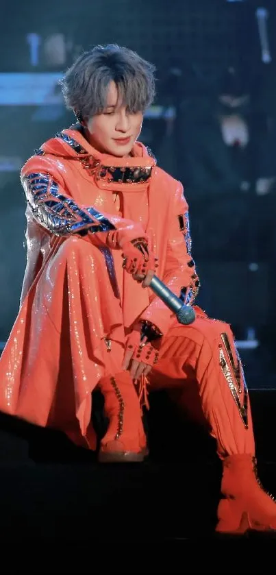 Energetic stage performer in orange outfit on stage under bright lights.