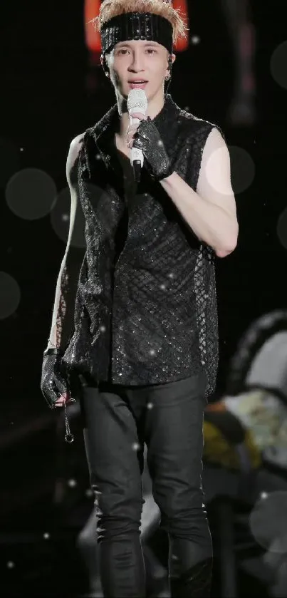 Dynamic stage performer in glittery black attire during a live concert.