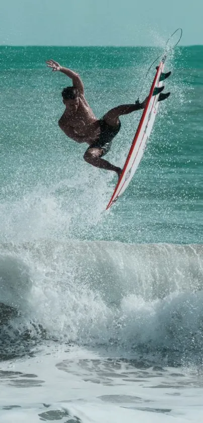 Surfer performs aerial maneuver above crashing ocean waves.