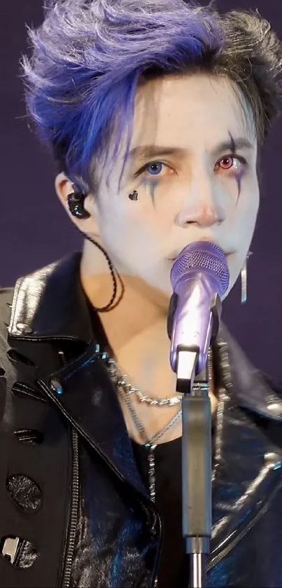 Artistic performer with blue hair and dramatic makeup on stage.