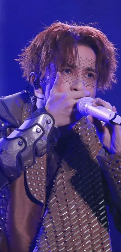 Performer in studded outfit onstage with microphone.