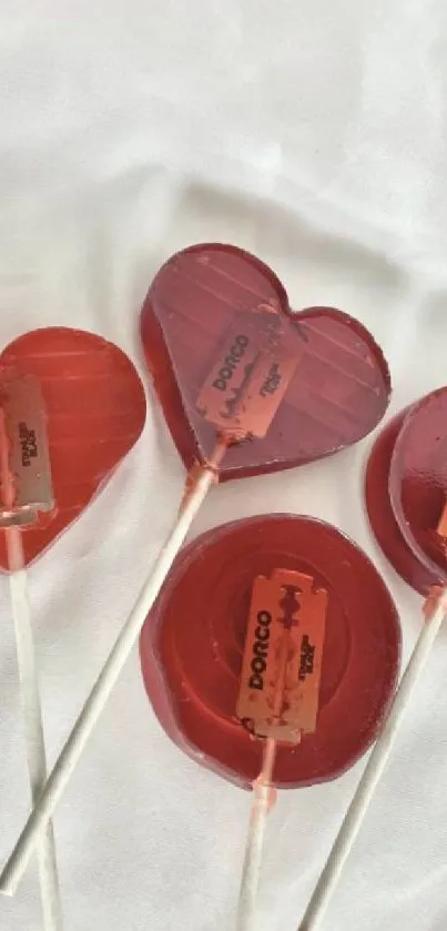 Red lollipops with razors on white background.