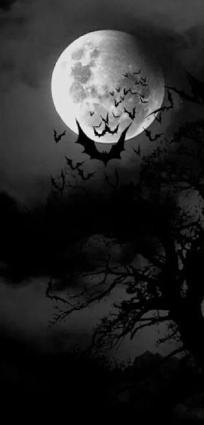 Full moon with bats and dark tree silhouette on a night sky.