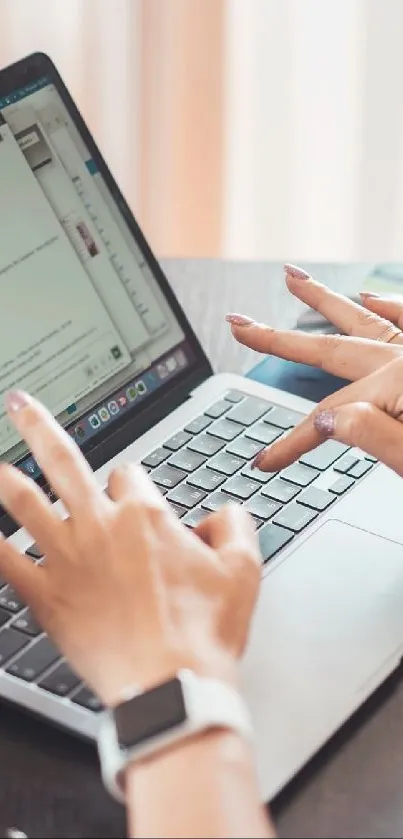 Hands typing on a laptop in a modern workspace setting.