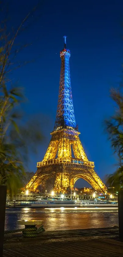 Eiffel Tower illuminated at night, framed by greenery.