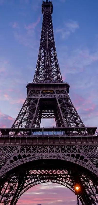 Eiffel Tower silhouetted against a pink and purple sunset sky.