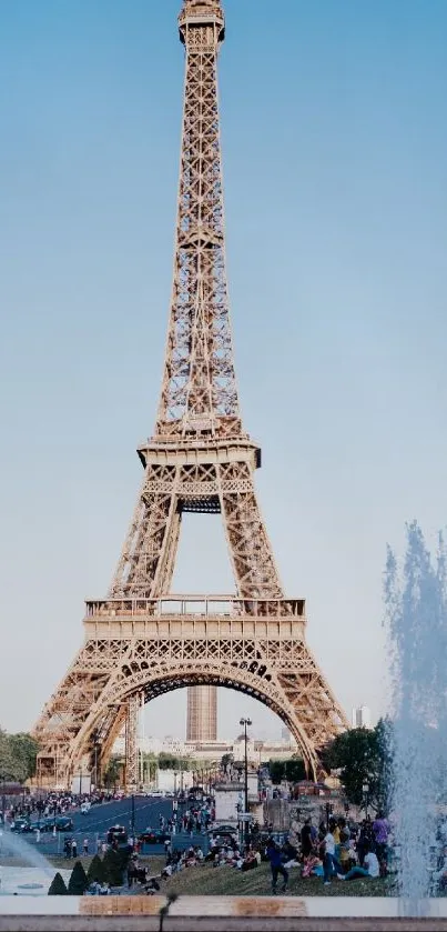 Eiffel Tower under a clear blue sky with fountains and tourists in the foreground.