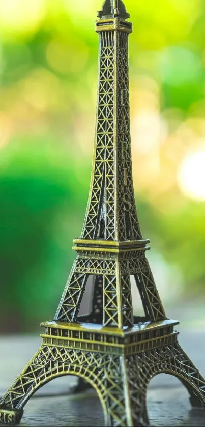 Miniature Eiffel Tower with green bokeh background on mobile wallpaper.