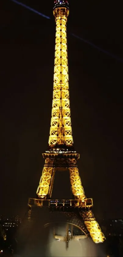 Eiffel Tower illuminated at night with bright lights and a dark sky.