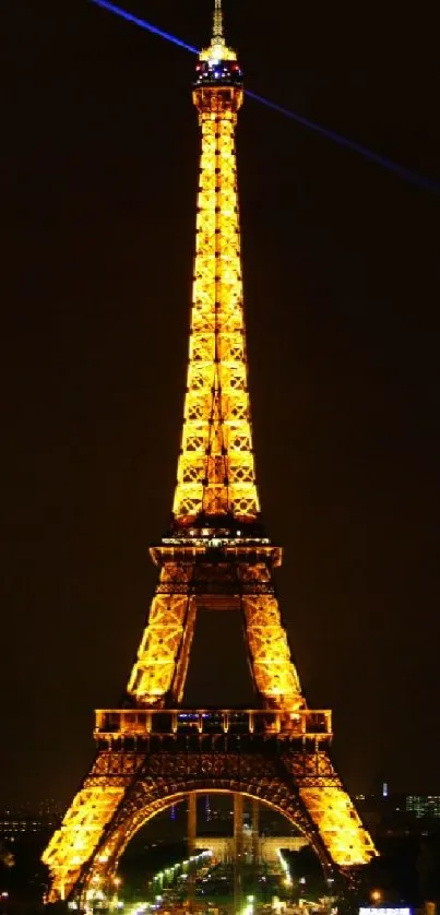 The Eiffel Tower illuminated at night in golden hues against a dark sky.