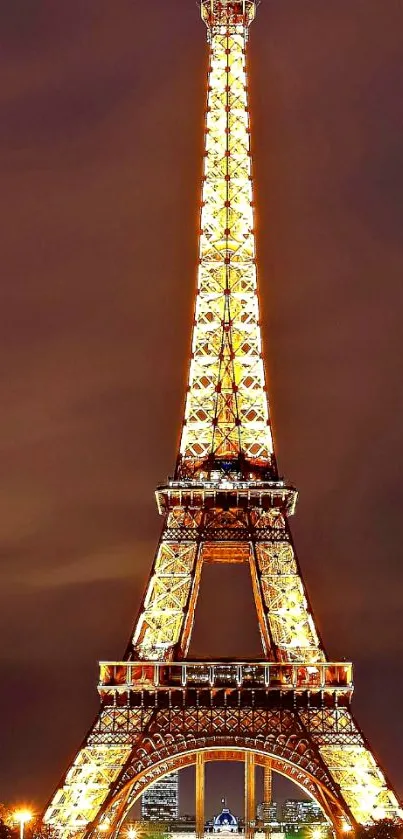 Eiffel Tower beautifully lit at night against a brown sky.