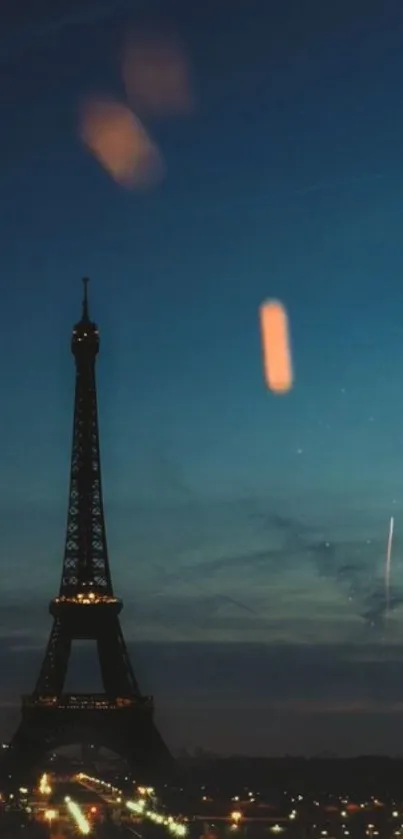 Eiffel Tower at night with lights and a dark blue sky.