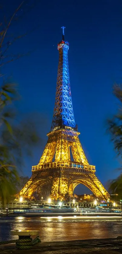 Eiffel Tower lit up at night with blue sky and greenery.