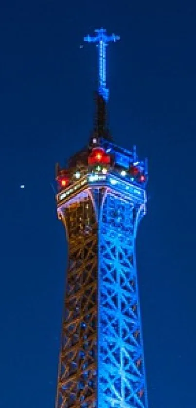 Night view of Eiffel Tower illuminated against blue sky.