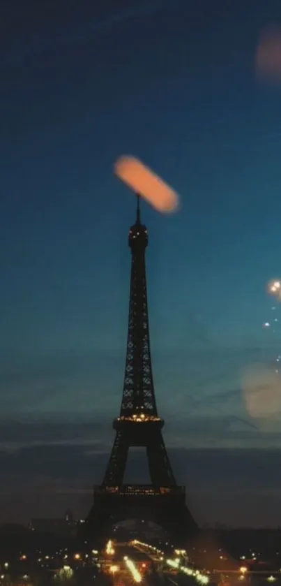 Eiffel Tower against dark blue night sky with city lights.