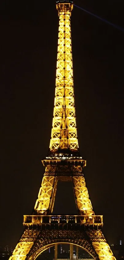 Eiffel Tower illuminated at night with a golden glow, set against the dark sky.