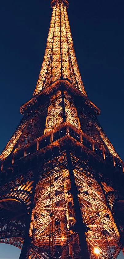 Eiffel Tower glowing at night against a dark sky.