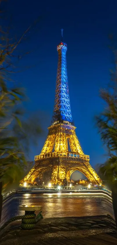 Eiffel Tower illuminated against a night sky, framed by greenery.