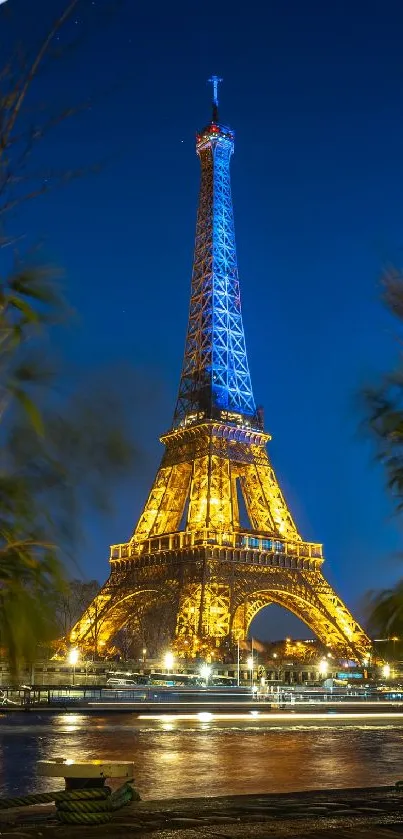 Eiffel Tower illuminated at night with blue sky backdrop.