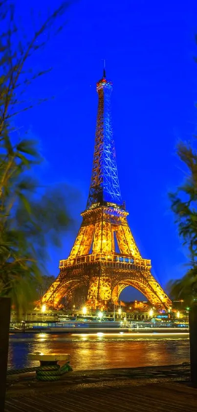 Eiffel Tower glowing at night with blue sky and urban scenery.