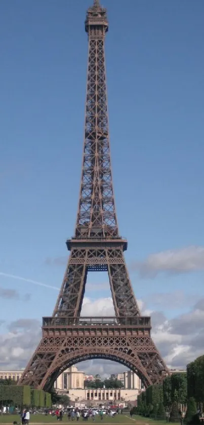 Eiffel Tower under a bright blue sky with lush green surroundings.