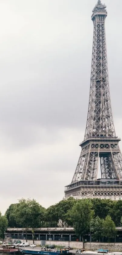 Eiffel Tower in Paris with Seine River under a cloudy sky.