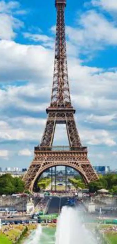 Eiffel Tower under a bright blue sky with clouds and greenery.