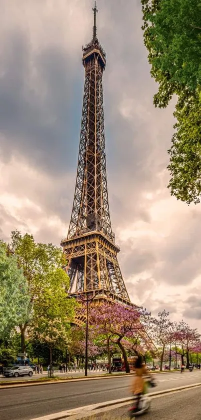 Eiffel Tower with lush spring trees and cloudy sky.