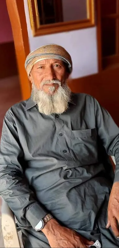 Elderly man in traditional attire sitting calmly at home.