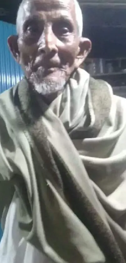 Serene portrait of an elderly man in a shawl with a blue background.