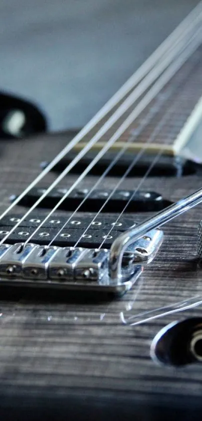 Close-up of an electric guitar focusing on strings and bridge in gray tones.