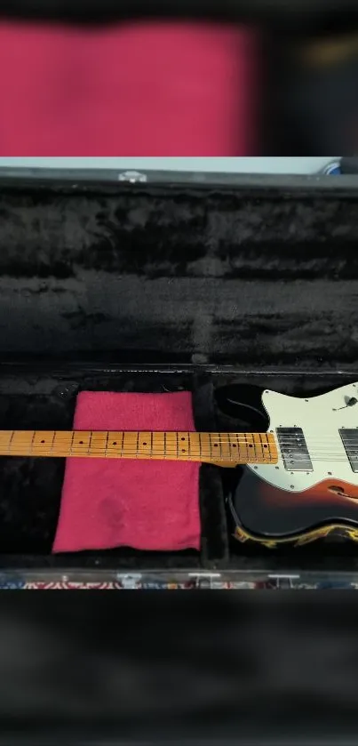 Electric guitar resting in a black case with a red cloth accent.