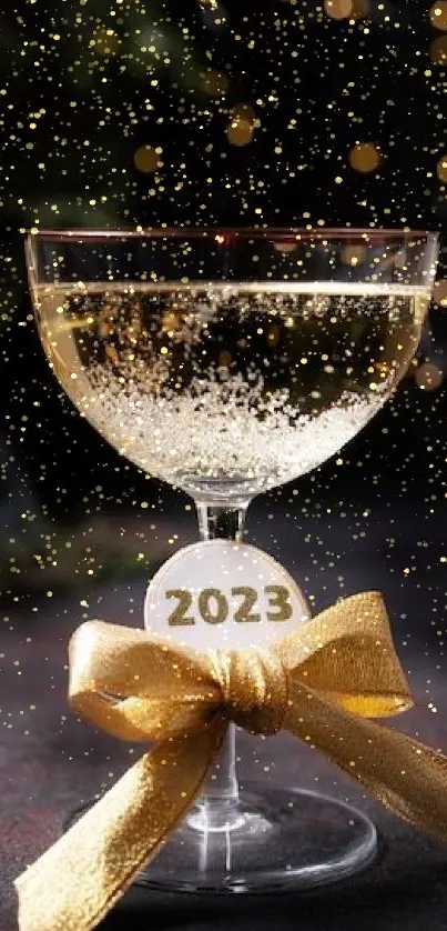 Elegant 2023 champagne glass with gold ribbon and bokeh lights.