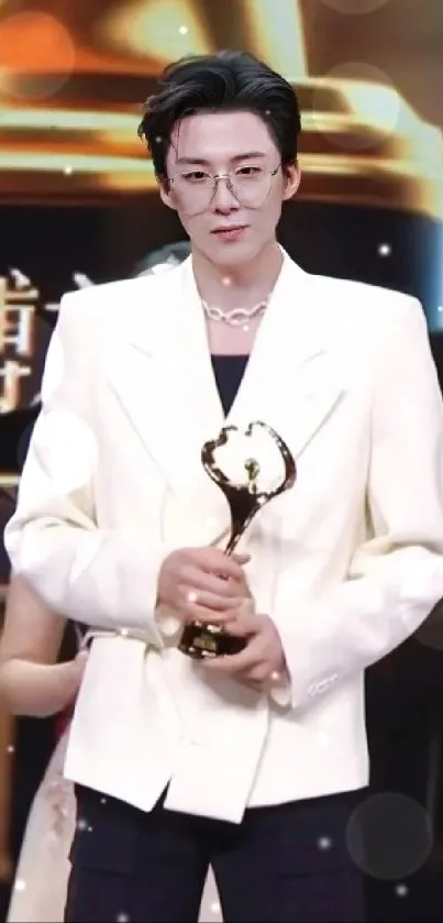 Person in elegant attire holding a trophy at an award ceremony.