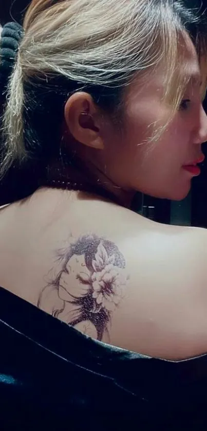 Elegant tattoo design on woman's back with soft lighting.