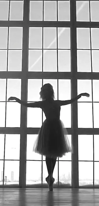 Silhouette of a ballerina posing gracefully against a large window.