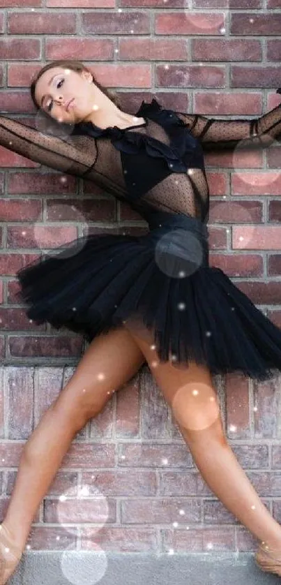 Ballet dancer in black tutu against brick wall, elegant pose.