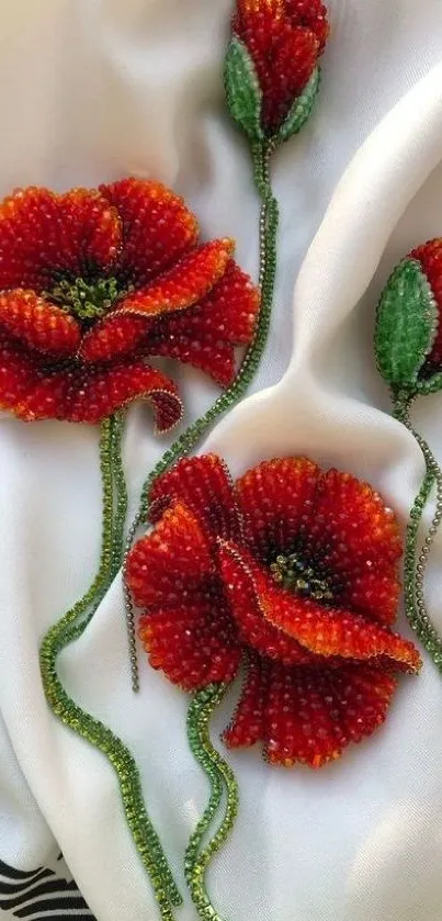 Beaded red flowers on white fabric background.