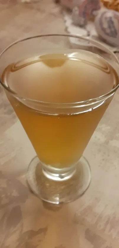 Glass of golden beverage on a light table.