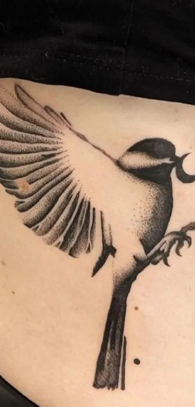 Black ink bird tattoo on skin background.