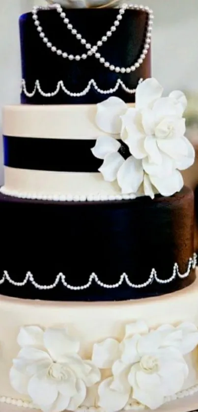 Elegant black and white cake with floral and pearl decorations.