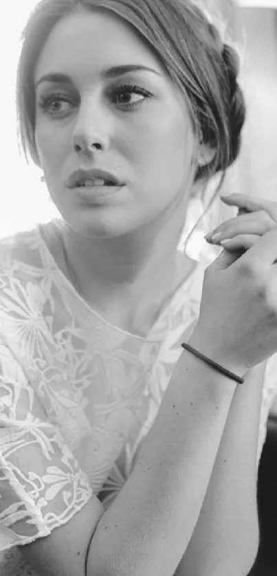 Black and white portrait of a thoughtful woman sitting indoors.