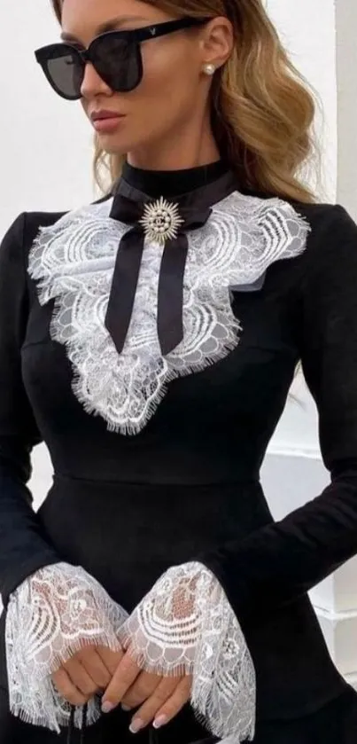 Woman in black dress with white lace details and sunglasses.