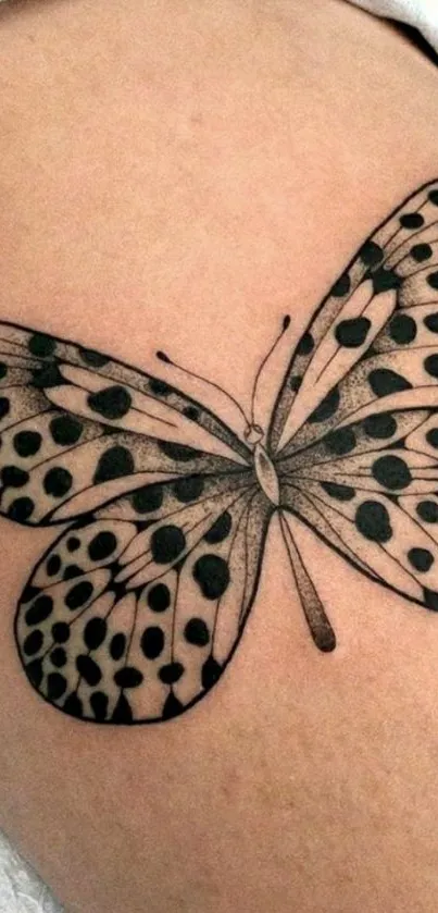 Elegant black butterfly tattoo on beige background.